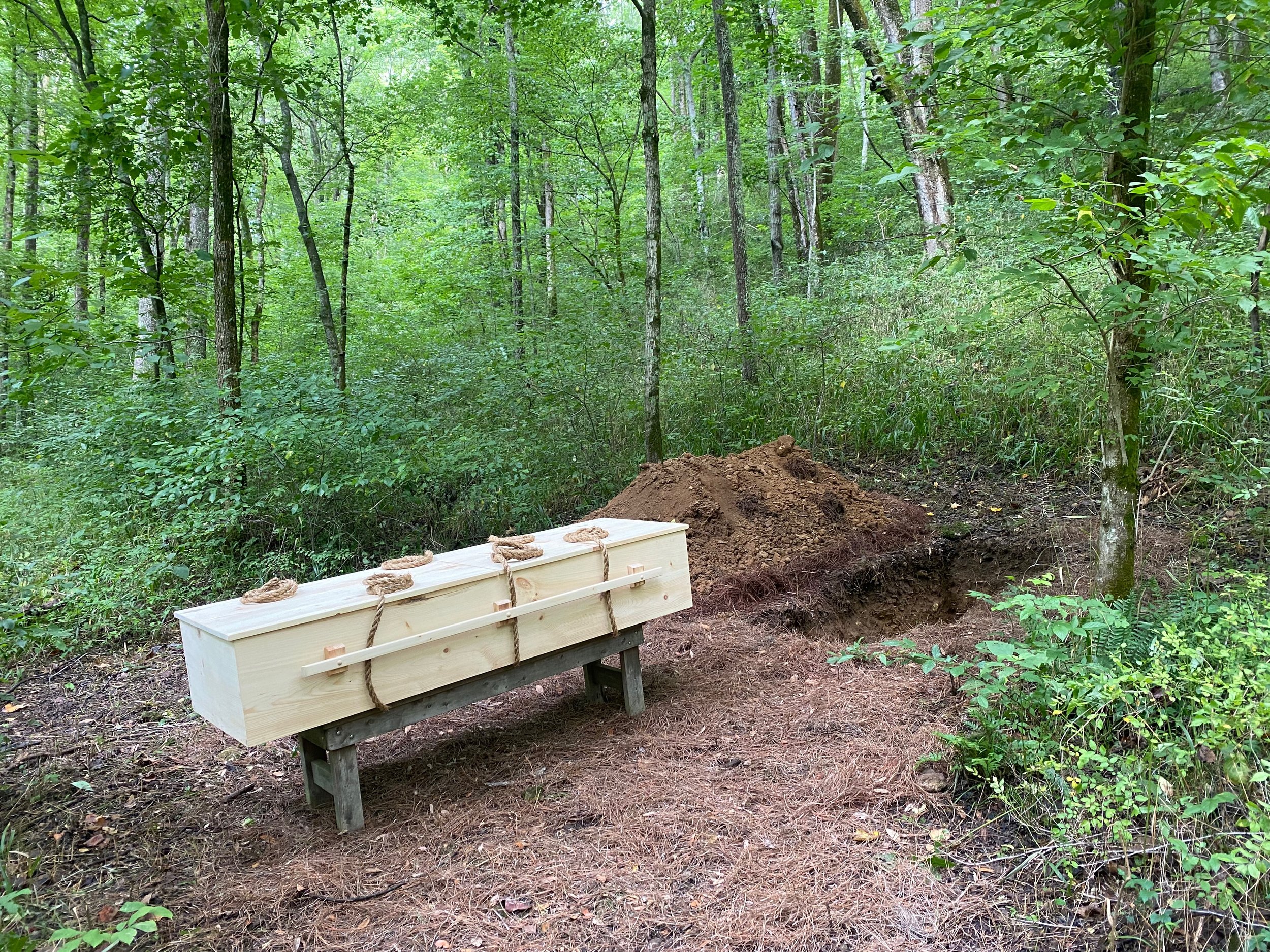  A pine casket rests on a bench in the woods at Larkspur before a natural burial. 