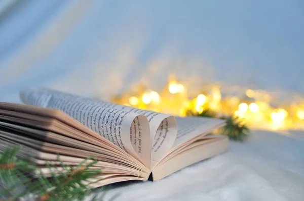  A book open with its pages folded in the shape of a heart in front of holiday lights. 
