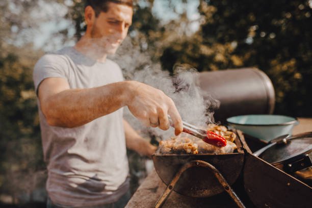  A man grills out meat on a sunny day in memory of his father. 