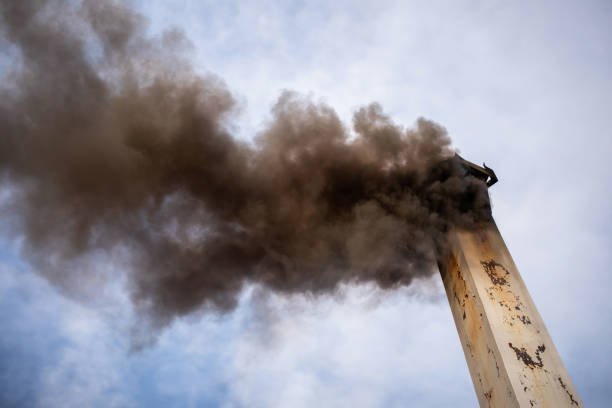 A chimney from a crematorium blasts black, polluted smoke into the air.