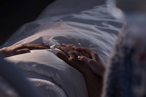  A person spends time holding the hand of their loved one after a death. 